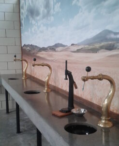 Image shows three brass taps and a black bottle capper