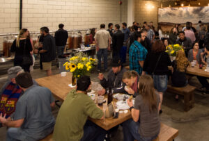 Image is of a group of people at a party at the brewery